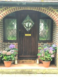 Front door and porch of bungalow with flowers and wreath