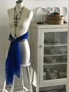 mannequin with necklaces and scarf on painted bar stool with vintage china cabinet