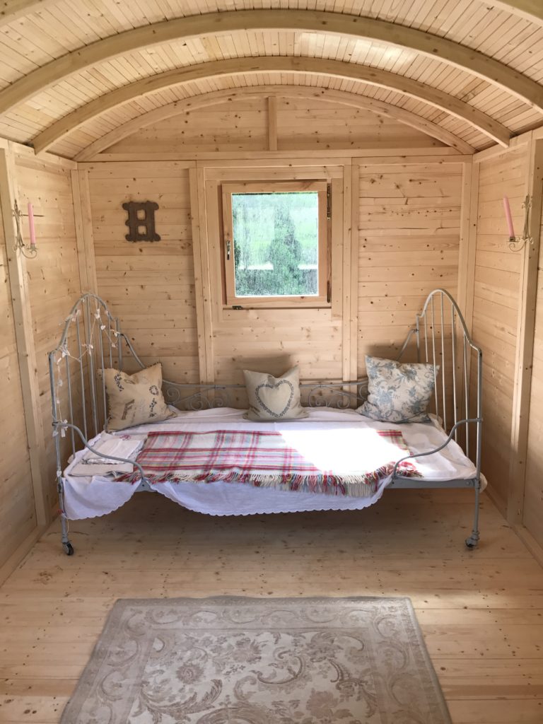 French iron bed and cushions and linens in shepherd's hut