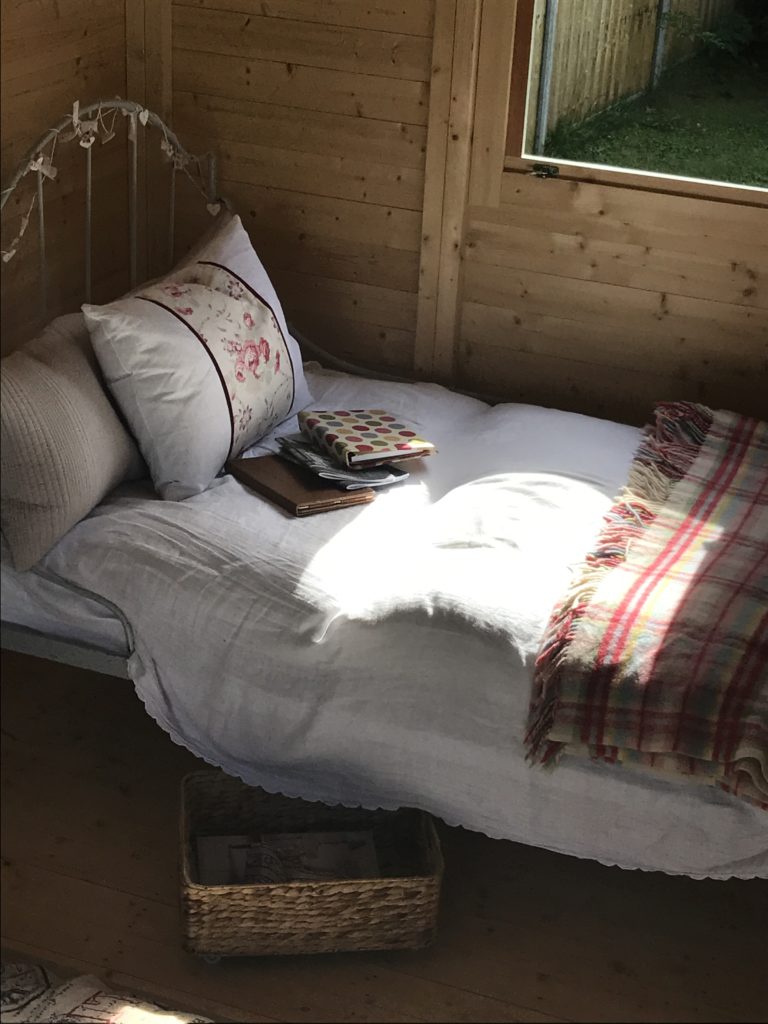 French iron bed and cushions and linens in shepherd's hut