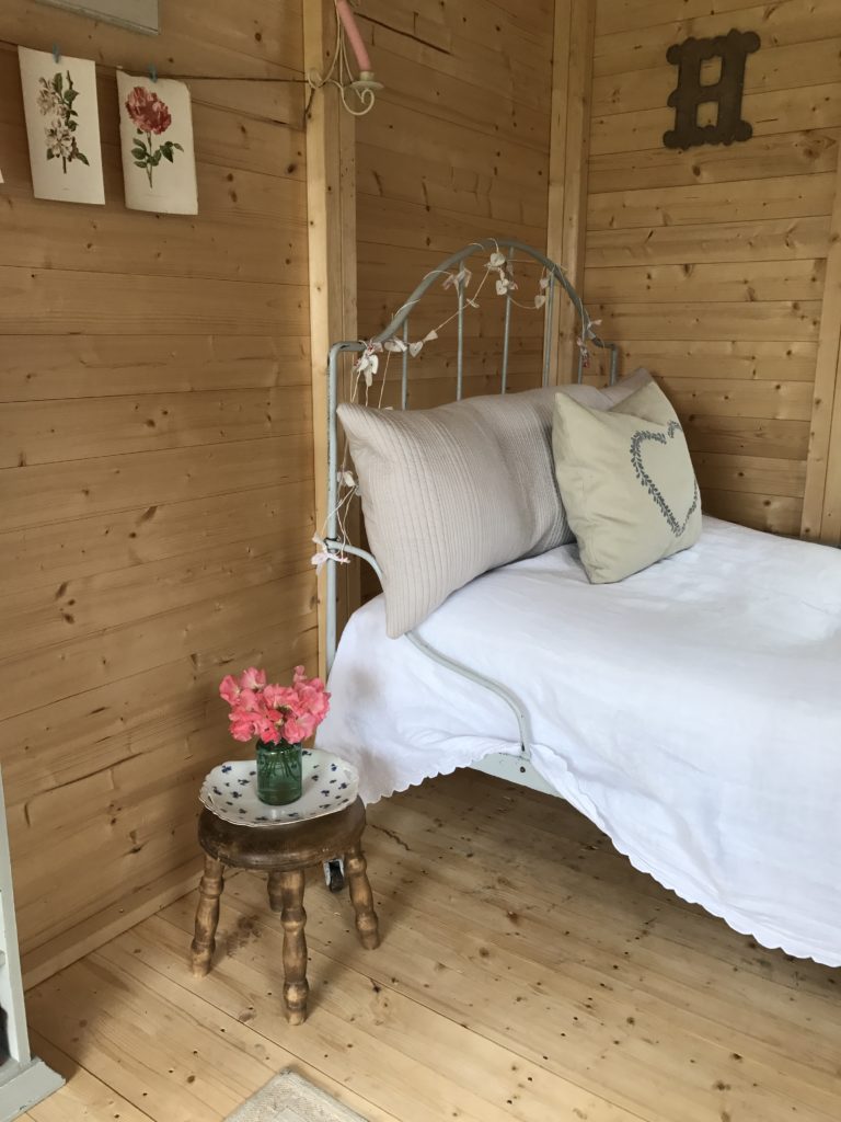 French iron bed and cushions and linens in shepherd's hut