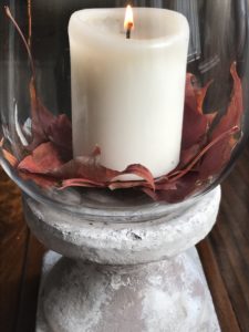 candle in hurricane lamp with leaves for halloween decoration ideas