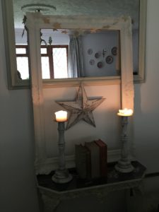 candlesticks books and star on console table with mirror and frame in faffing session