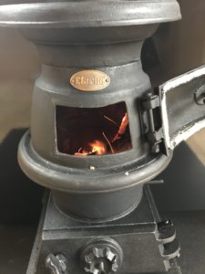 pot bellied stove with fire lit and door open