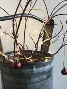 twig christmas tree with baubles and lights in metal bucket for christmas decorations