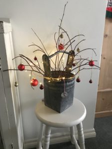 twig christmas tree with baubles and lights in metal bucket for christmas decorations