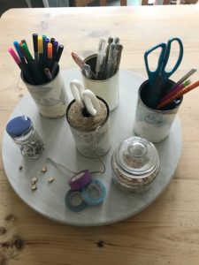 painted lazy susan with wallpapered tin cans scissors washi tape pens pencils and wooden hearts