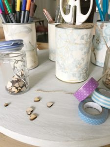 painted lazy susan with wallpapered tin cans scissors washi tape pens pencils and wooden hearts