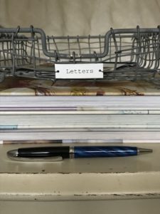 wire letter tray, coffee table books and a pen for handwritten letters