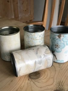 four tin cans covered in blue wallpaper samples