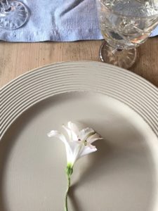 distressed plate charger with white flower and wine glass