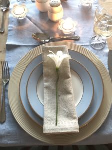 distressed plate charger with napkin and blue plates, white flower and candles