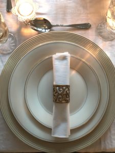 distressed plate charger with white plates, napkin and gold napkin ring