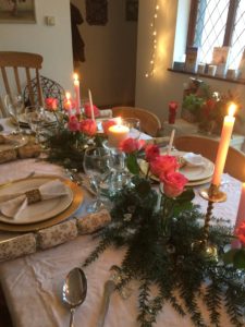 gold plate chargers at christmas dining table with pink candles and roses