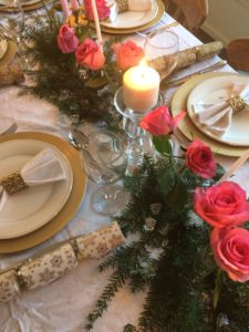 gold plate chargers at christmas dining table with pink candles and roses