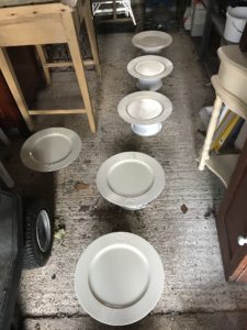 six spray painted plate chargers drying in garage