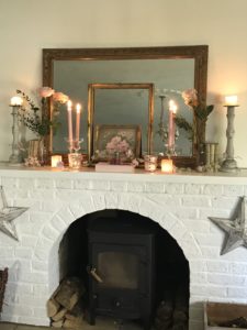 pink roses candles vintage french books rose garland and gilt mirror and frames on white painted fireplace