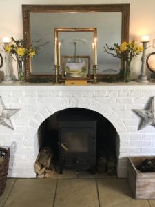 distressed star on white painted fireplace with mirror frames daffodils wreath books candles stars and wood burner