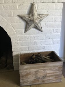 distressed star on white painted fireplace with vintage wooden box of kindling