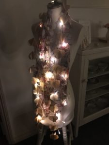 mannequin dressed in many paper garland with fairy lights at night