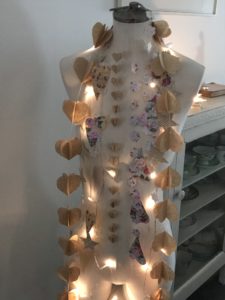 many pretty paper garlands around mannequin neck with fairy lights