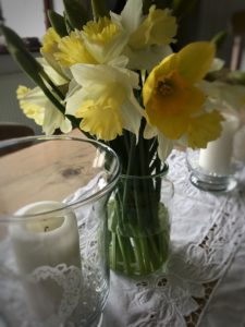 daffodils and candles on lace table runner