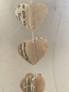 tiny paper hearts stitched together with book sheets to make paper garland