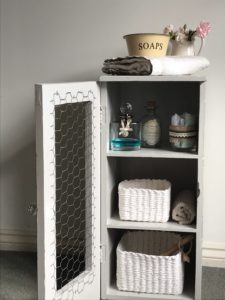 completed makeover of grey painted pot cupboard with baskets bottles and bathroom paraphenalia 