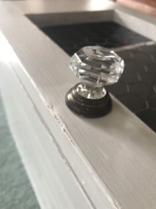 vintage glass door knob on door of grey painted pot cupboard and chicken wire