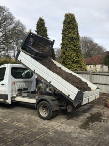 white pick up dumps top soil on concrete for vegetable garden