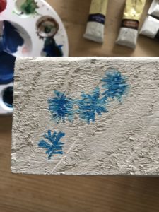 painting blue cornflower design on homemade sign