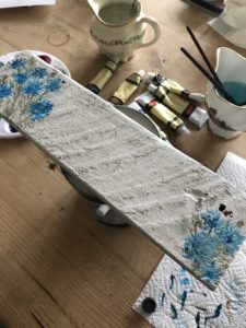 painting blue cornflower design on homemade sign