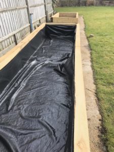 lined raised beds made from sleepers in vegetable garden