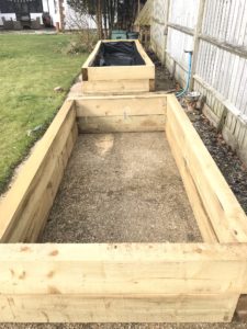 raised beds made from sleepers on concrete base in vegetable garden