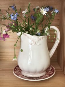 small cream jugs with spring flowers on pink plate