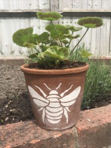 vintage terracotta pot with stenciled bee and geranium for garden tray