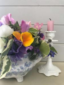 simple flower arrangement using fresh cut flowers with pink candle in white candlestick