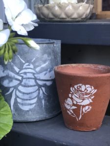 terracotta pot and zinc jug with bee and flower stencils for pot decoration