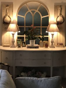 sitting room sideboard and mirror display with rose and lavender wreaths on shutters at night