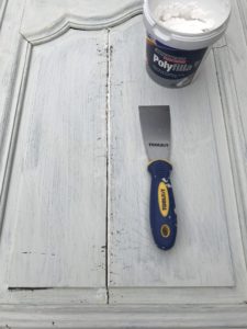 cracks on primed rustic armoire door being filled