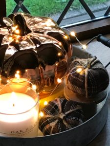 shiny orange pumpkin with mini brown pumpkins and candle and fairy lights for autumn decor