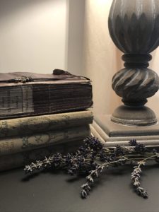 vintage french books on grey painted linen storage cabinet with lavender and lamp detail