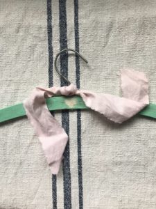 green painted wooden hanger with pink ribbon and heart motif