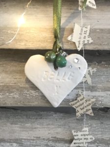 heart clay christmas decoration with jewells and paper star garland and lights on shutter background