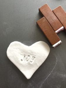 clay decoration heart with mini letter stamps spelling joy