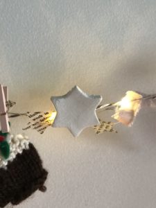 star clay decorations with pegs and paper star garland and twinkle lights