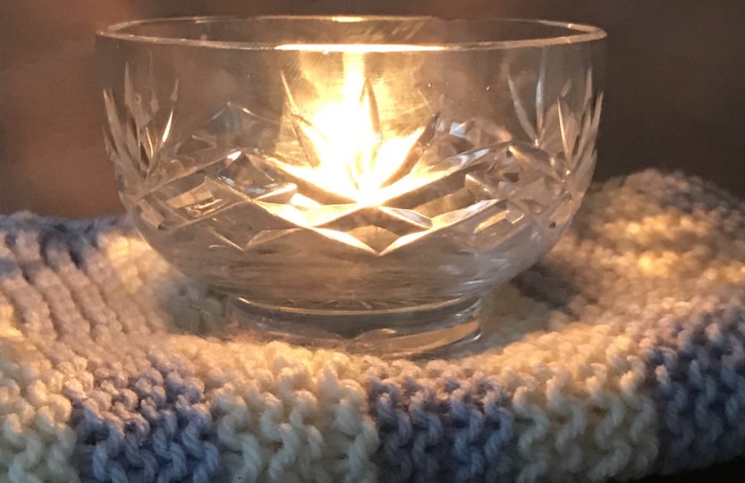 glass bowl and candle and knitted blanket