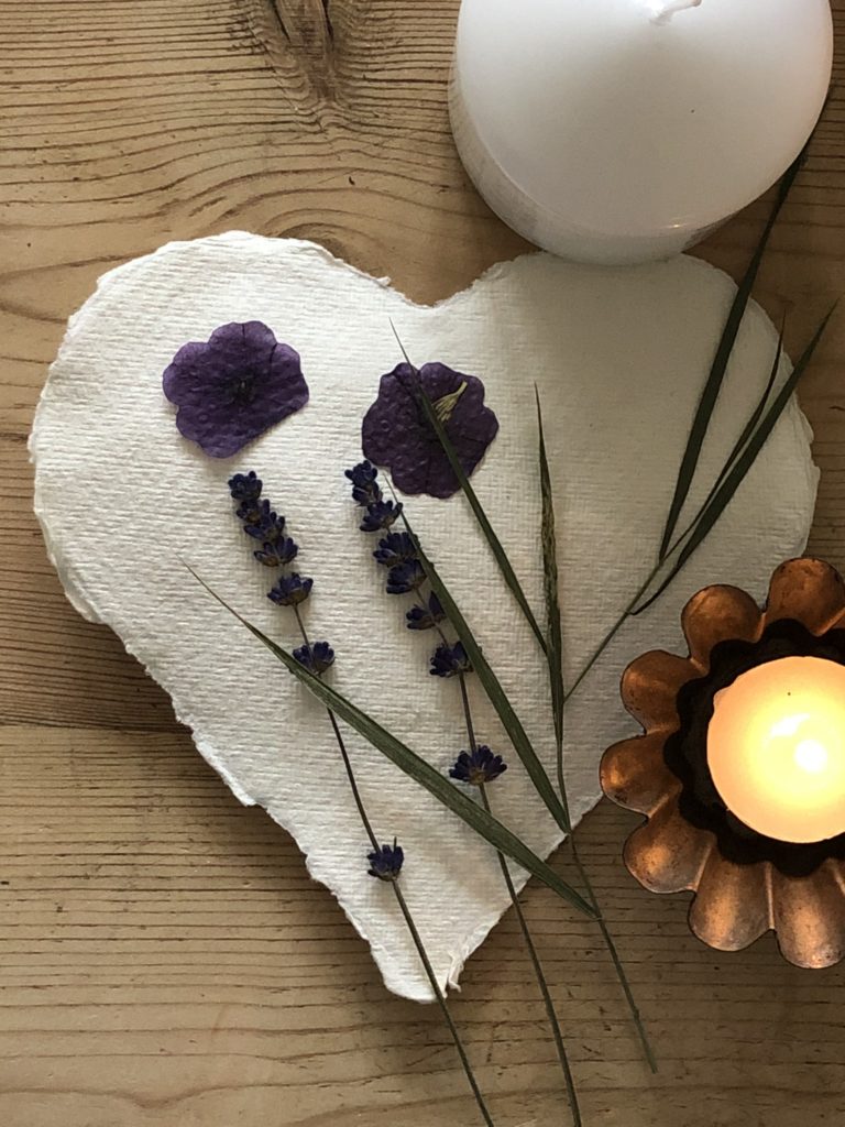 flatlay of dried pressed flowers on paper heart with tealight for pressed flower craft