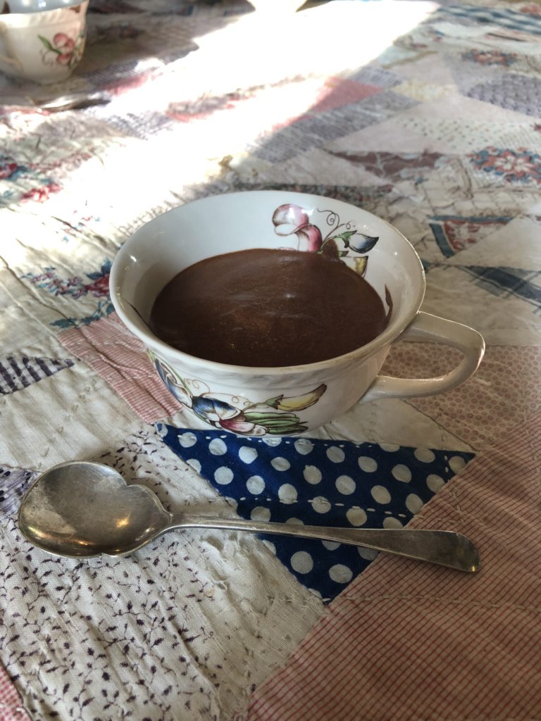 chocolate mousse in vintage teacup with vintage spoon on vintage fabric