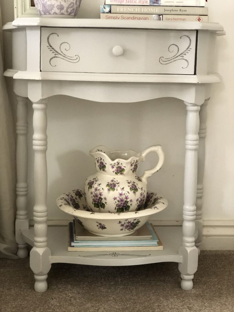 painted and stencilled bedside table with pretty jug and bowl and books